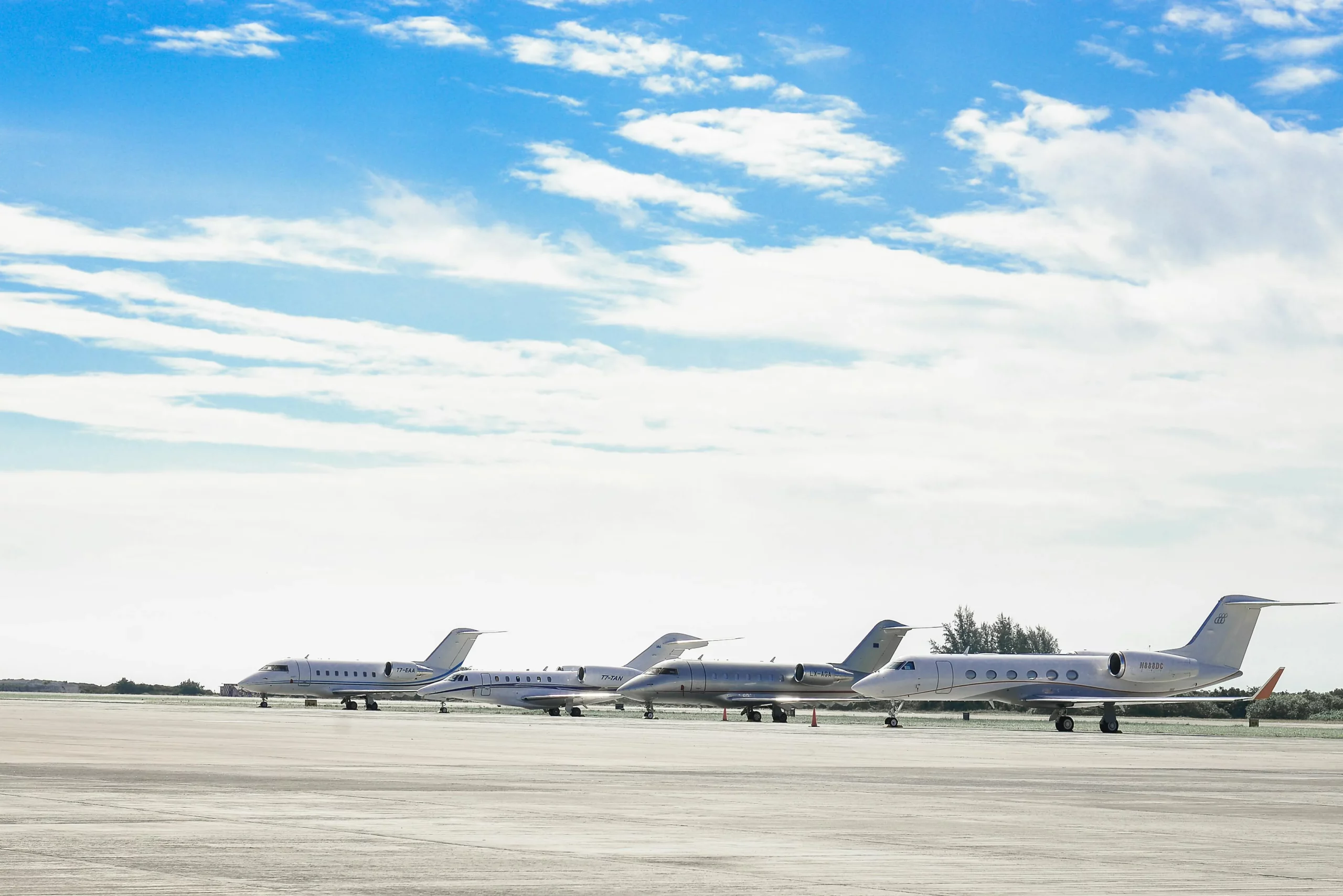 Four luxury private jets lined up on the tarmac at dusk
